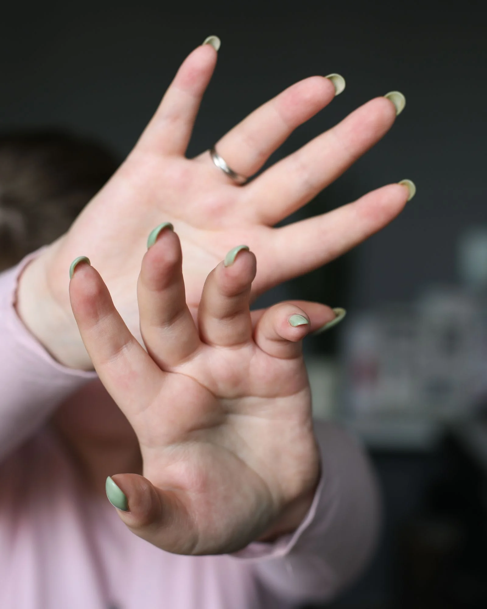 Hands showing a nude manicure with green French tips in natural light